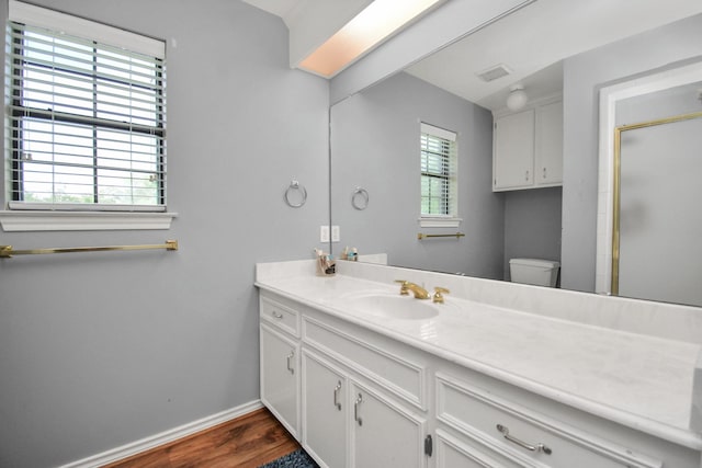 bathroom with toilet, wood finished floors, visible vents, vanity, and baseboards