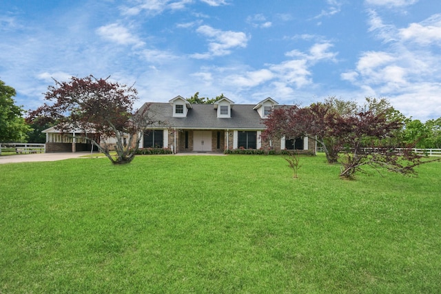 cape cod home with a carport, a front yard, concrete driveway, and brick siding