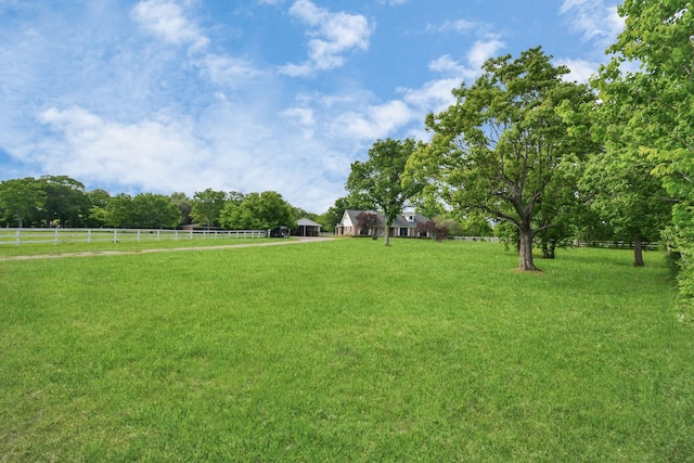 view of yard with fence and a rural view