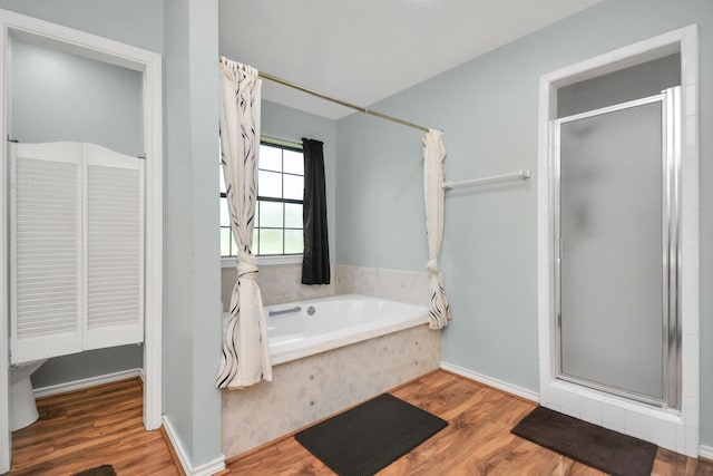 bathroom with a garden tub, a shower stall, and wood finished floors