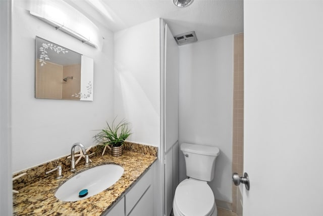 bathroom with toilet, a textured ceiling, vanity, and visible vents