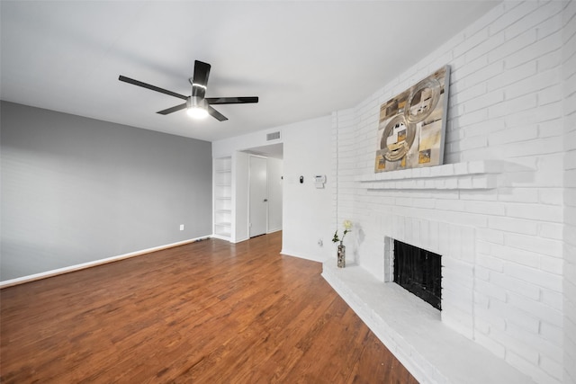 unfurnished living room featuring a brick fireplace, ceiling fan, baseboards, and wood finished floors