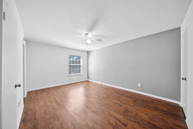 unfurnished room with a ceiling fan, dark wood finished floors, and baseboards