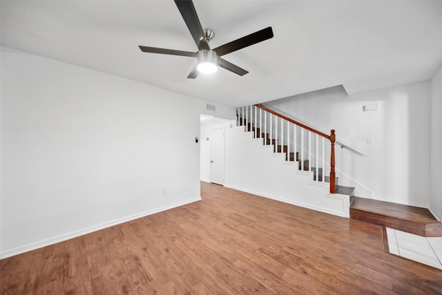 unfurnished living room featuring visible vents, ceiling fan, wood finished floors, baseboards, and stairs