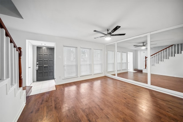 foyer entrance with light wood-style flooring, stairway, baseboards, and a ceiling fan