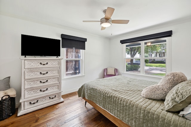 bedroom with a ceiling fan, wood-type flooring, baseboards, and crown molding