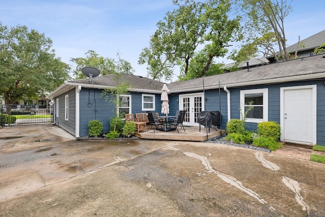 rear view of house with roof with shingles, french doors, and a wooden deck