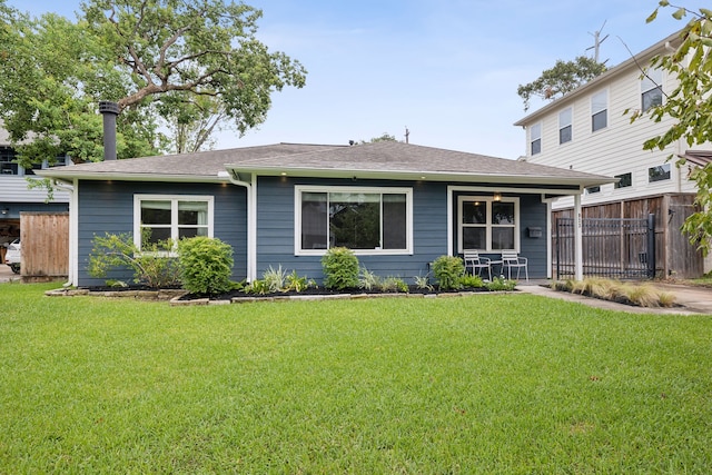 view of front facade with covered porch, a front lawn, roof with shingles, and fence