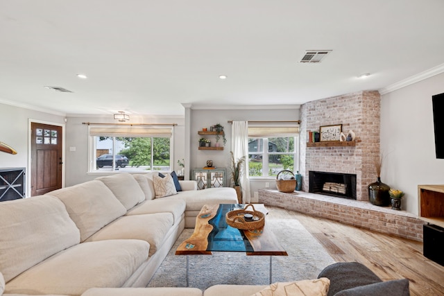 living room with a fireplace, wood finished floors, visible vents, and crown molding