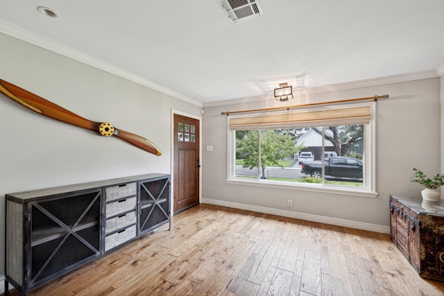 entryway with baseboards, light wood-style flooring, visible vents, and crown molding