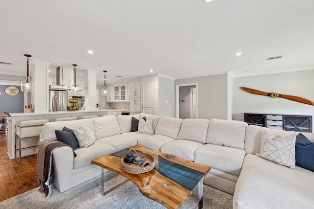 living area with hardwood / wood-style floors, visible vents, crown molding, and recessed lighting