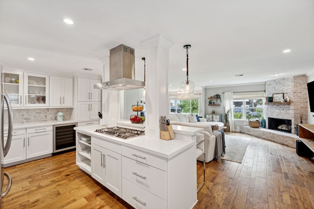 kitchen with beverage cooler, island exhaust hood, white cabinetry, and open floor plan