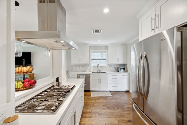 kitchen with tasteful backsplash, visible vents, island range hood, appliances with stainless steel finishes, and a sink