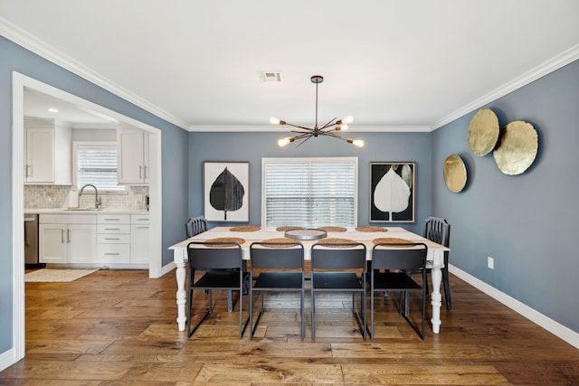 dining space with crown molding, a notable chandelier, visible vents, baseboards, and hardwood / wood-style flooring