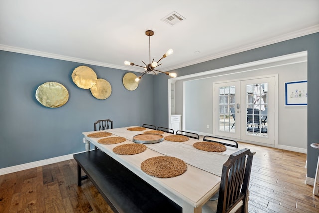 dining room featuring baseboards, wood-type flooring, visible vents, and crown molding