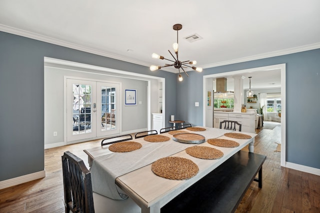 dining room featuring a chandelier, visible vents, crown molding, and hardwood / wood-style floors