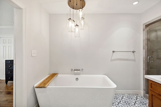 full bathroom featuring a stall shower, baseboards, tile patterned floors, vanity, and a freestanding tub