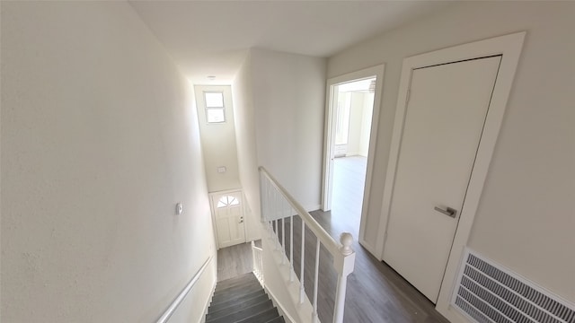 corridor with dark wood-style flooring, an upstairs landing, and visible vents