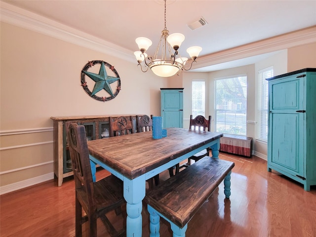 dining area featuring visible vents, a chandelier, wood finished floors, and ornamental molding