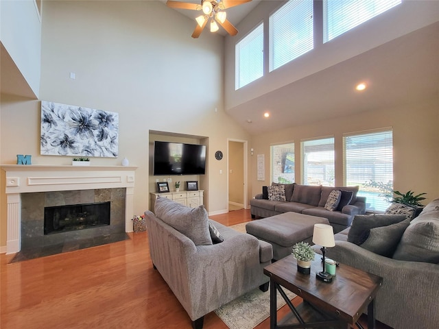 living room with ceiling fan, recessed lighting, baseboards, light wood-type flooring, and a tiled fireplace