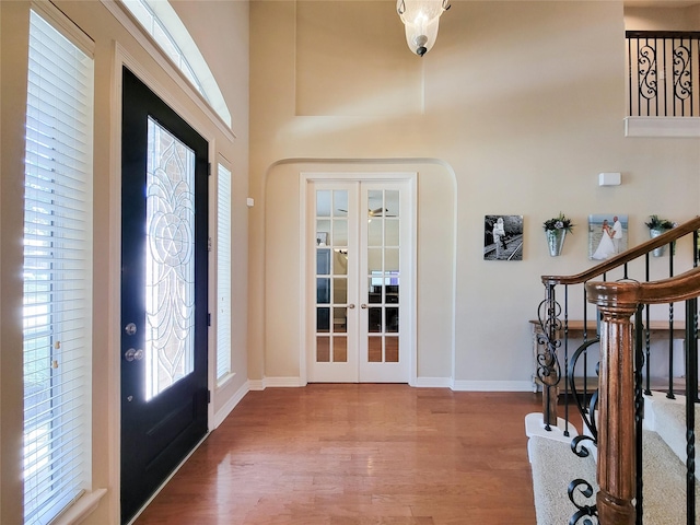 entrance foyer with stairs, french doors, wood finished floors, and baseboards