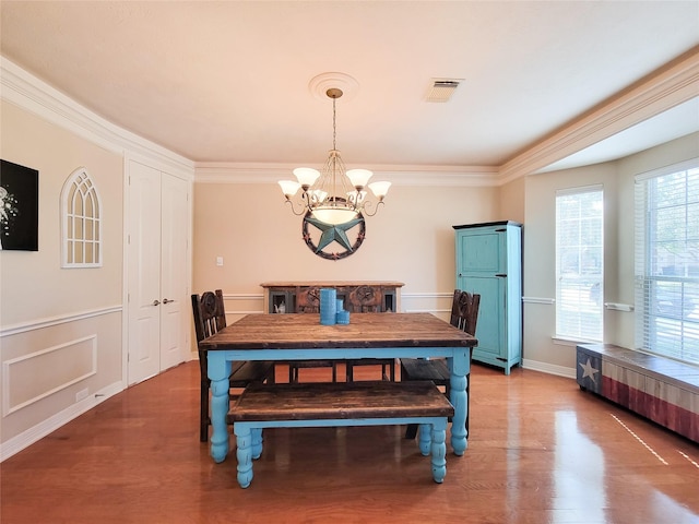 dining room with an inviting chandelier, visible vents, ornamental molding, and wood finished floors