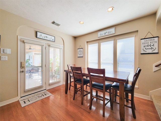 dining room with a textured ceiling, recessed lighting, wood finished floors, visible vents, and baseboards