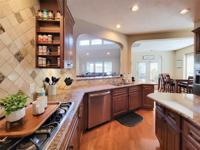 kitchen with light stone counters, gas cooktop, a sink, light wood-style floors, and dishwasher