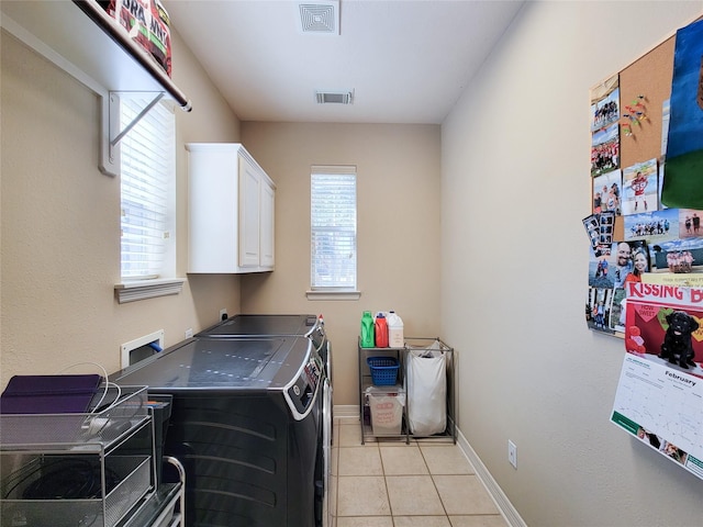 laundry area with cabinet space, light tile patterned floors, visible vents, washer and dryer, and a wealth of natural light