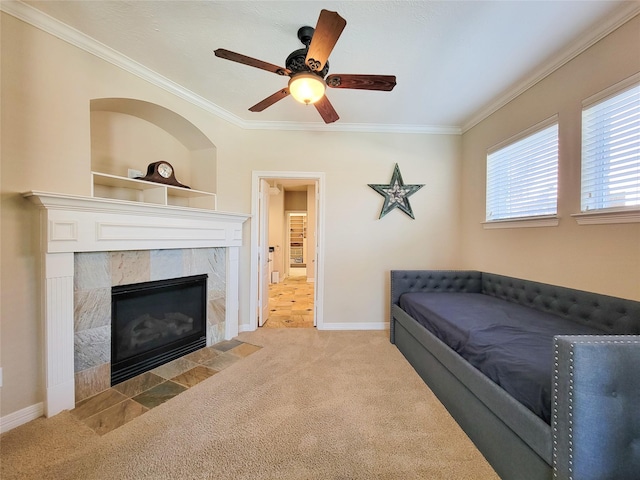 interior space featuring a tile fireplace, crown molding, baseboards, and ceiling fan