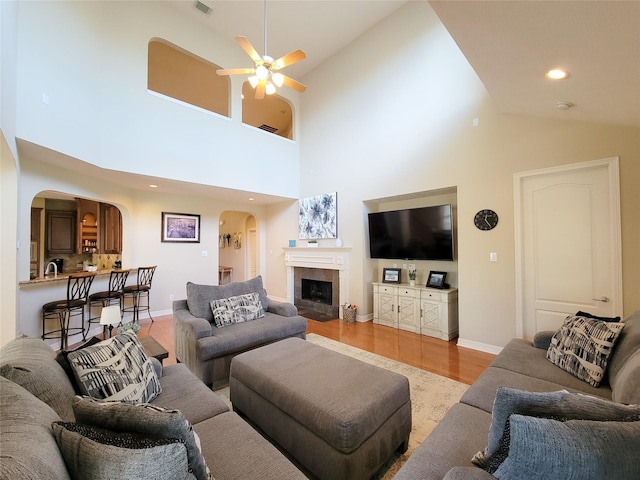 living room featuring arched walkways, recessed lighting, a fireplace, a ceiling fan, and light wood-type flooring