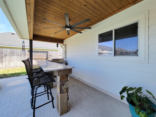 view of patio / terrace featuring outdoor dry bar, fence, and a ceiling fan