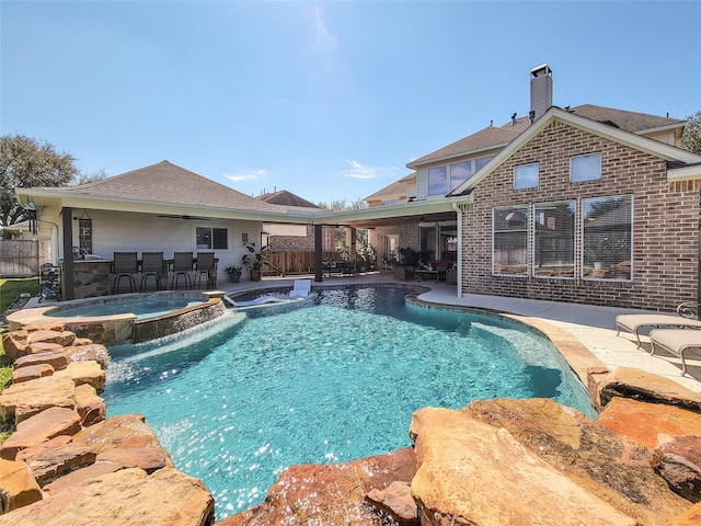 view of swimming pool featuring a patio area, a pool with connected hot tub, and fence