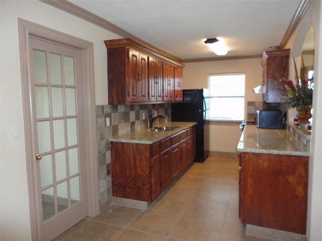 kitchen with crown molding, backsplash, a sink, and freestanding refrigerator