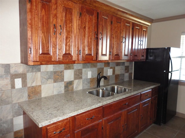 kitchen with light stone countertops, dark tile patterned flooring, a sink, ornamental molding, and decorative backsplash