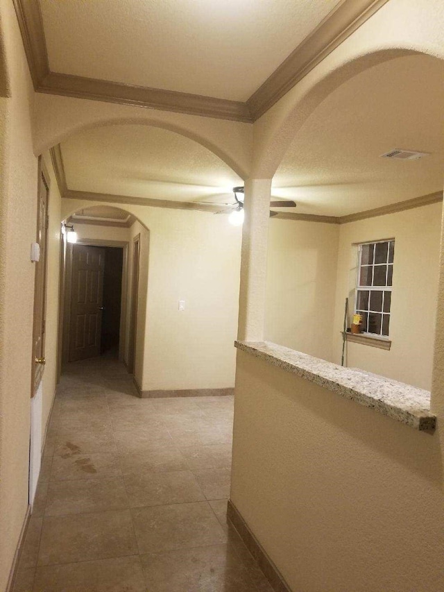 corridor featuring arched walkways, crown molding, and baseboards