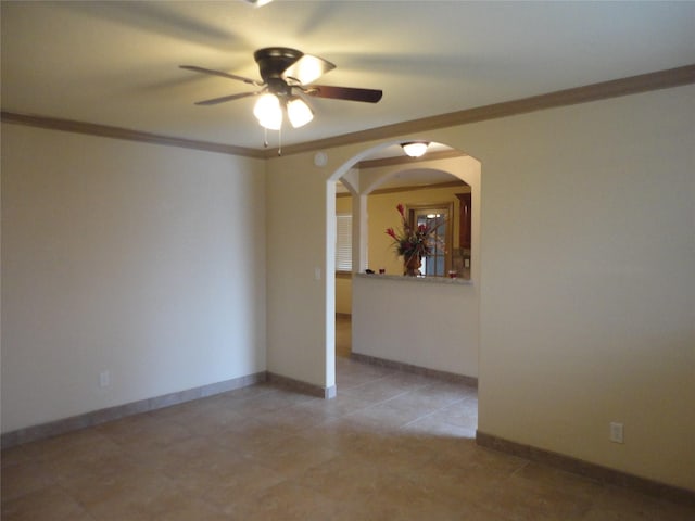 empty room with ornamental molding, arched walkways, baseboards, and a ceiling fan