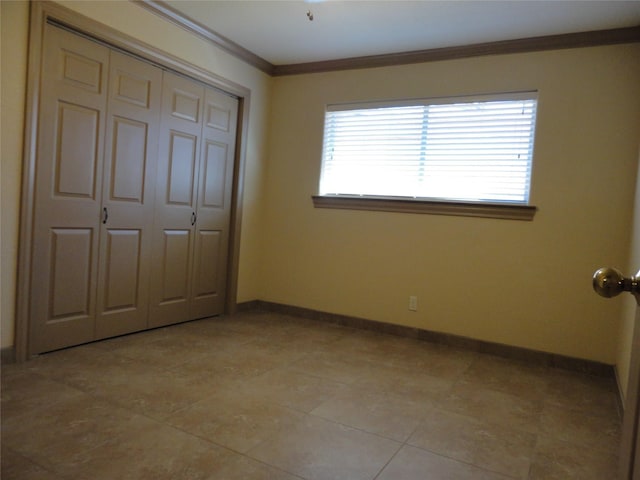 unfurnished bedroom with a closet, baseboards, and crown molding