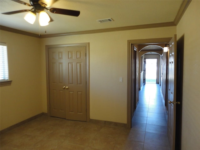 hall with light tile patterned floors, visible vents, arched walkways, baseboards, and ornamental molding