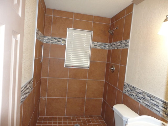 full bathroom featuring a tile shower, tile walls, and toilet