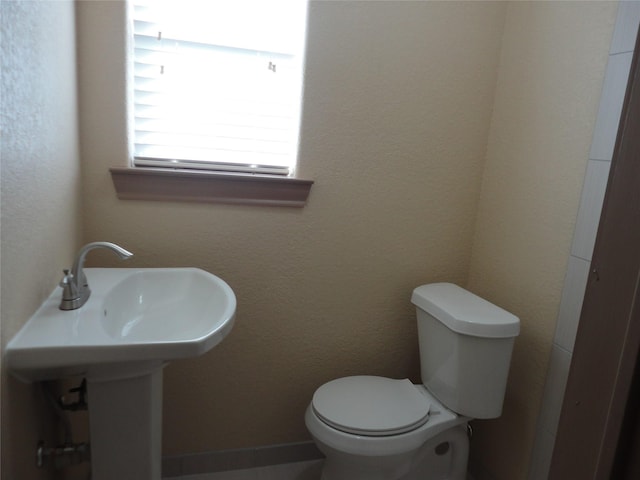 bathroom featuring a textured wall and toilet