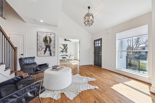 foyer entrance with wood finished floors, baseboards, high vaulted ceiling, stairs, and a chandelier