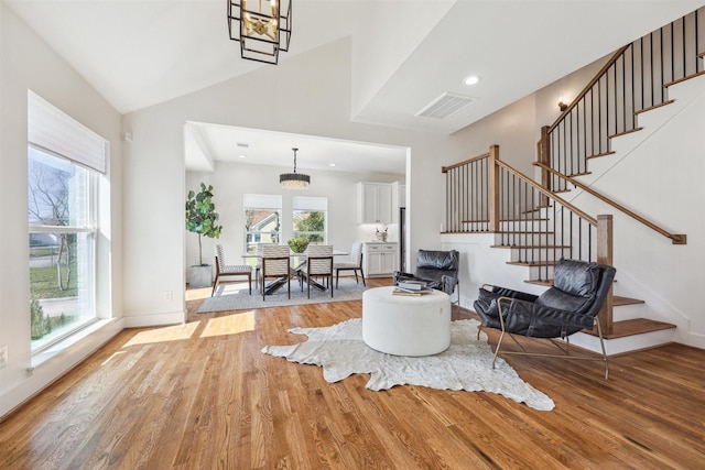 living area with a wealth of natural light, stairway, light wood-type flooring, and visible vents