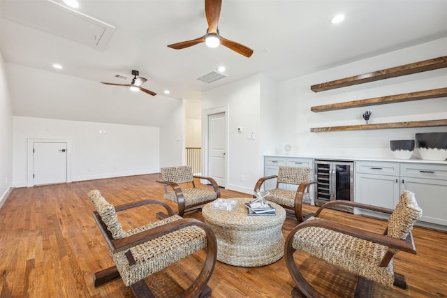 living area featuring ceiling fan, wine cooler, a dry bar, attic access, and wood finished floors