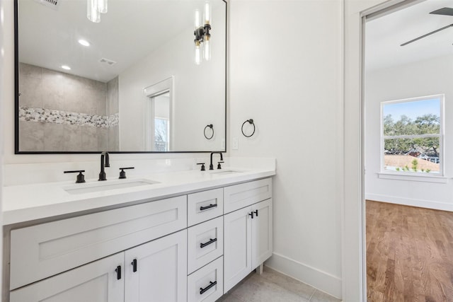 bathroom featuring a sink, baseboards, recessed lighting, and double vanity