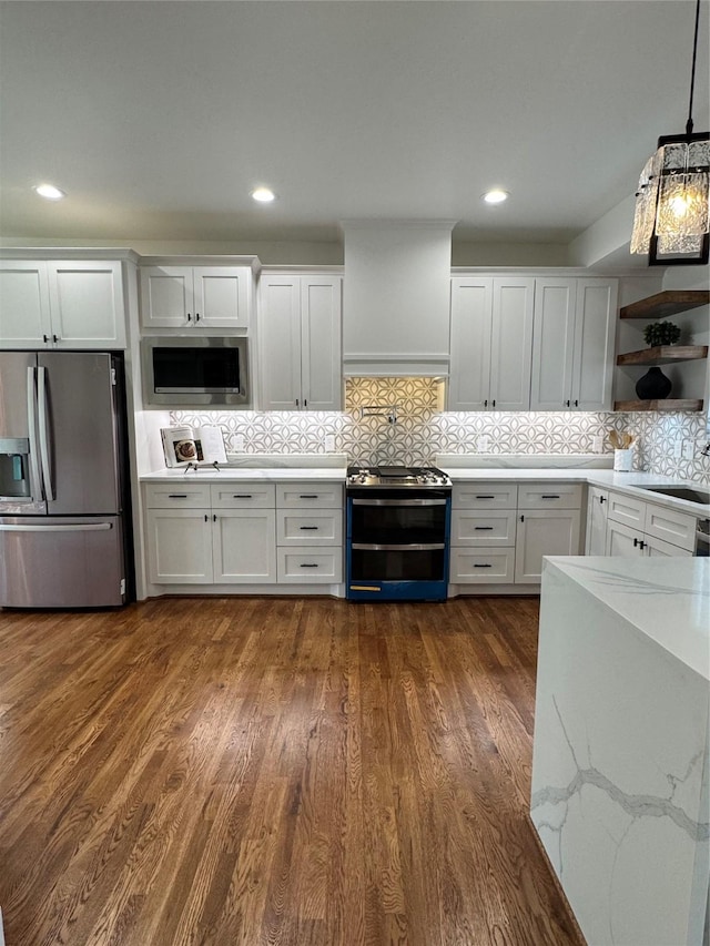 kitchen with stainless steel appliances, white cabinets, and dark wood finished floors