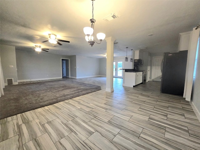 unfurnished living room featuring ceiling fan, decorative columns, visible vents, and baseboards