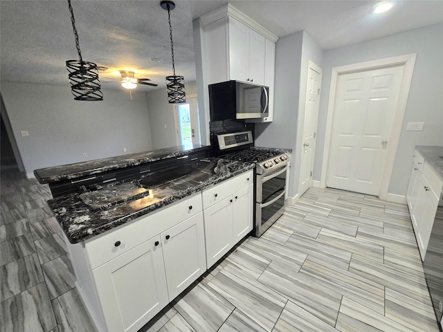 kitchen featuring white cabinetry, baseboards, double oven range, dark stone countertops, and pendant lighting