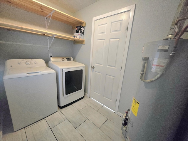 washroom with laundry area, water heater, and washing machine and clothes dryer