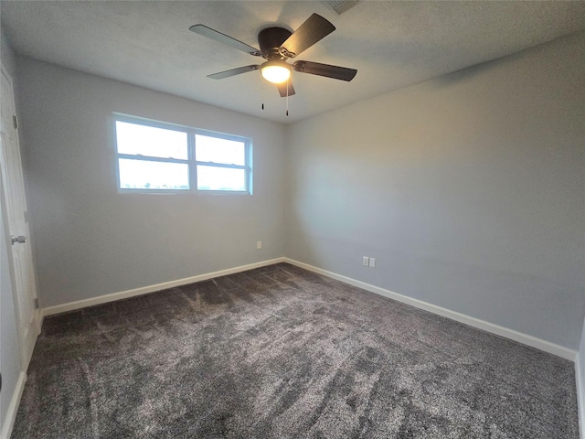 empty room with baseboards, dark carpet, and a ceiling fan